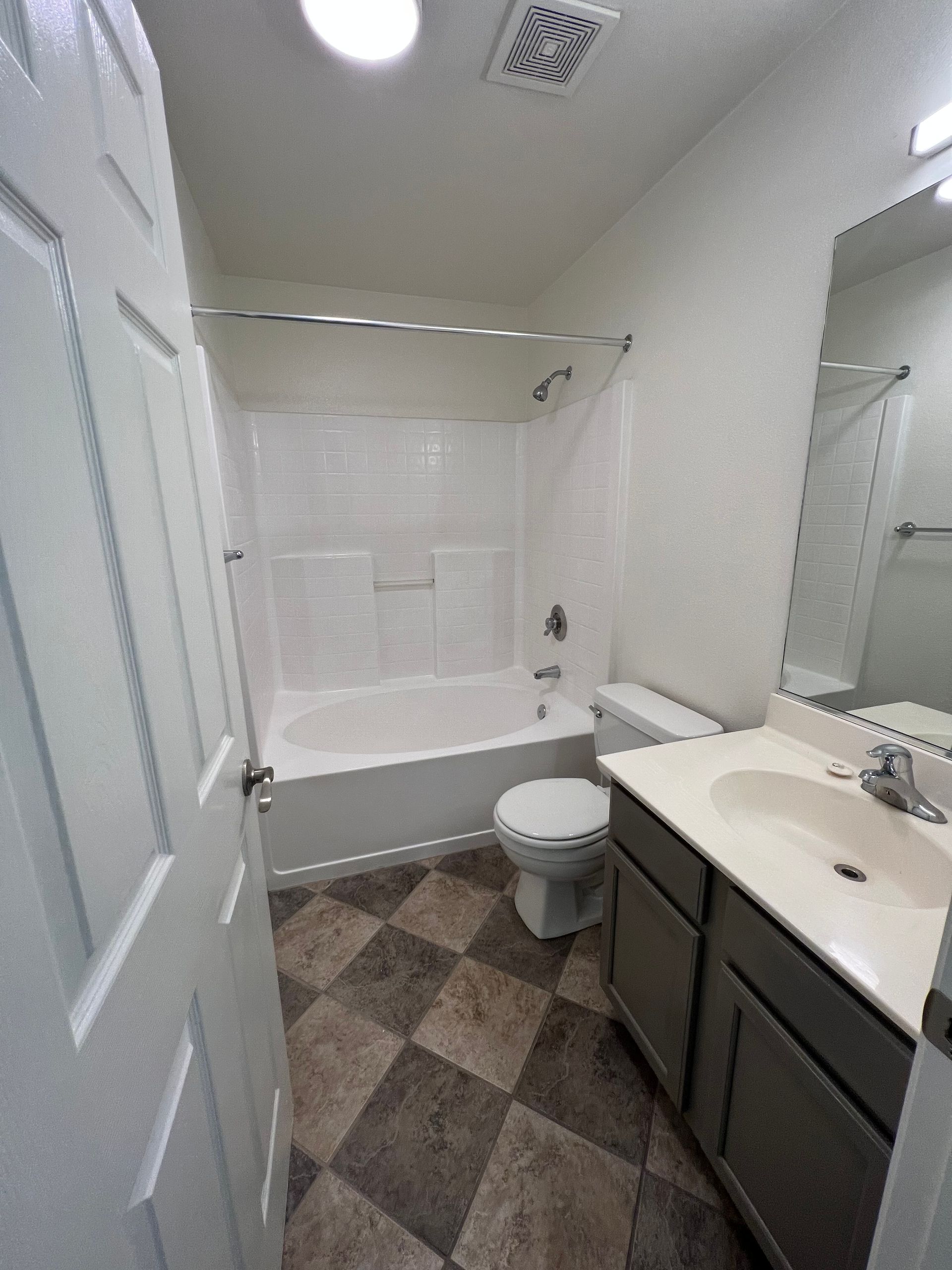 A bathroom with a tub , toilet , sink and mirror.