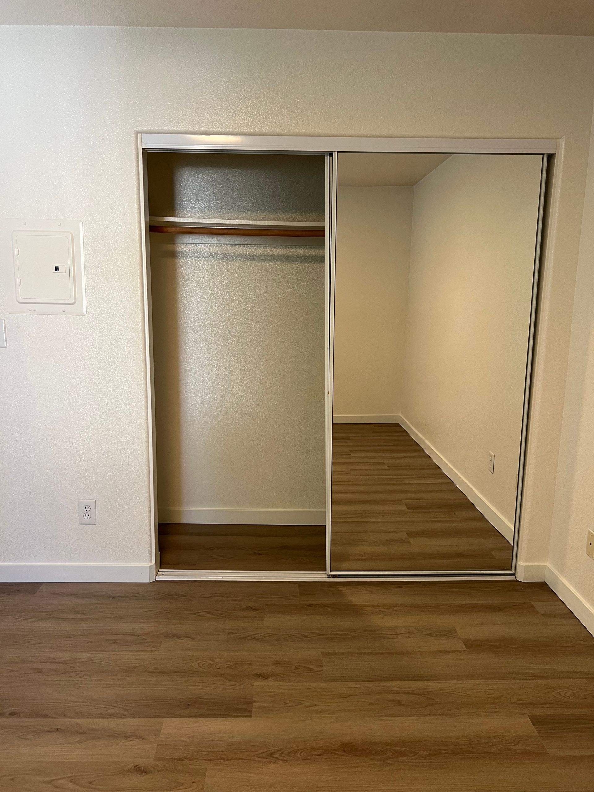 An empty room with a closet and a mirror.