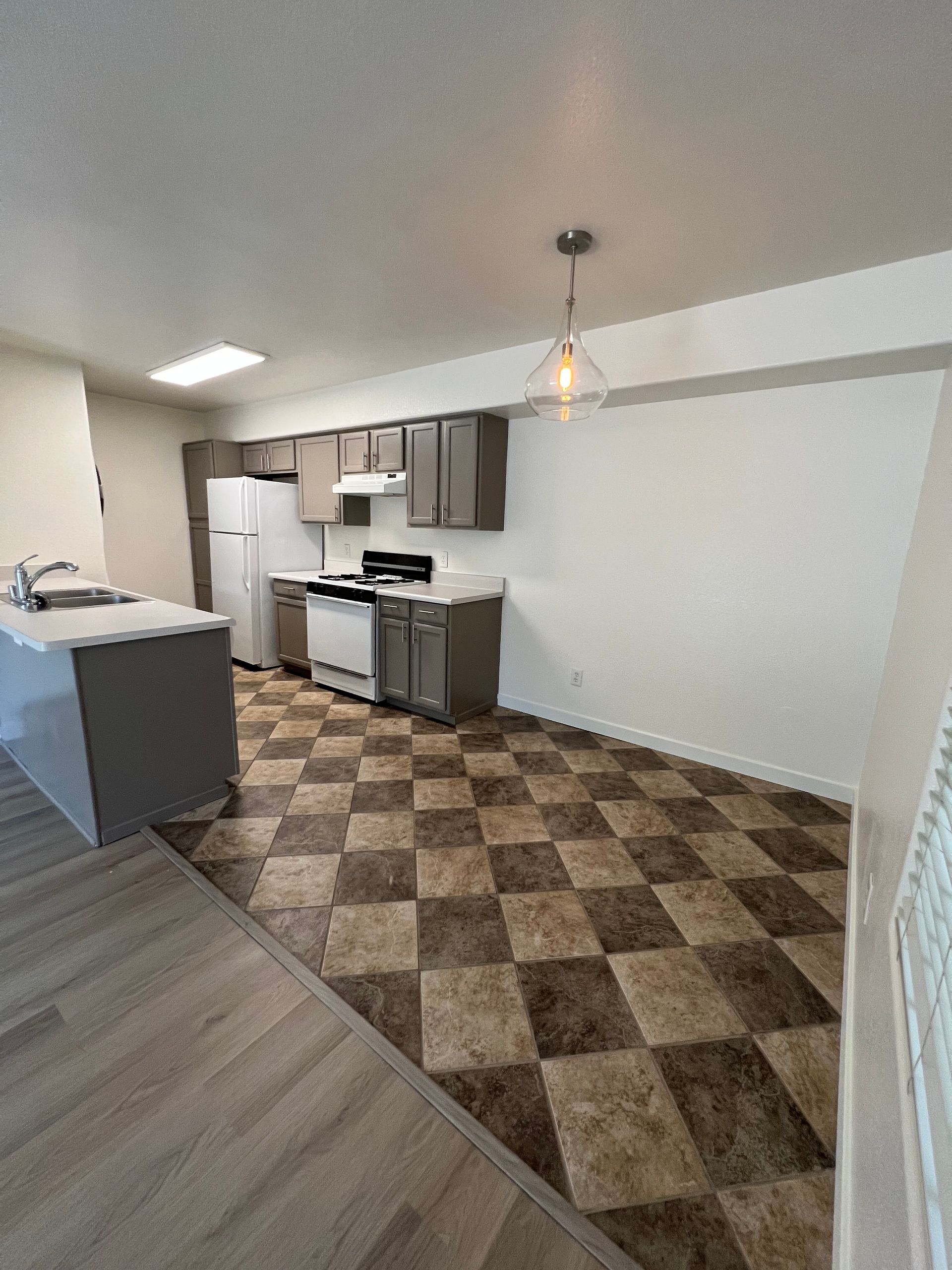 A kitchen with a checkered floor and a stove and refrigerator.