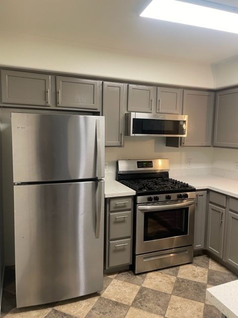 A kitchen with stainless steel appliances and gray cabinets