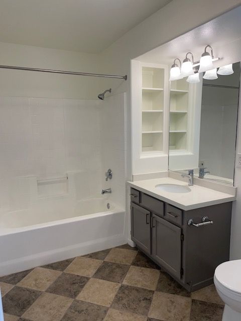 A bathroom with a tub , sink , toilet and mirror