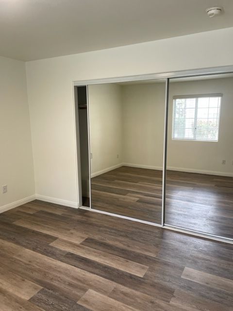 A bedroom with hardwood floors and sliding mirrored doors.