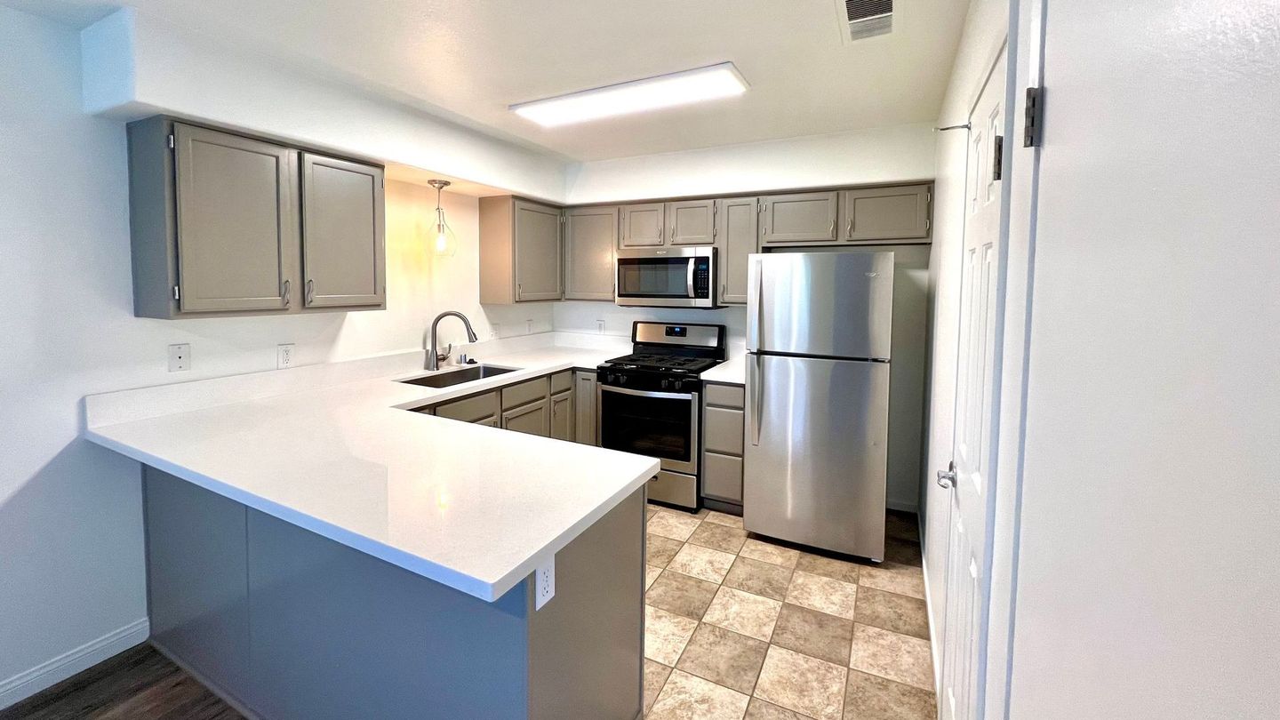 A kitchen with stainless steel appliances and gray cabinets.