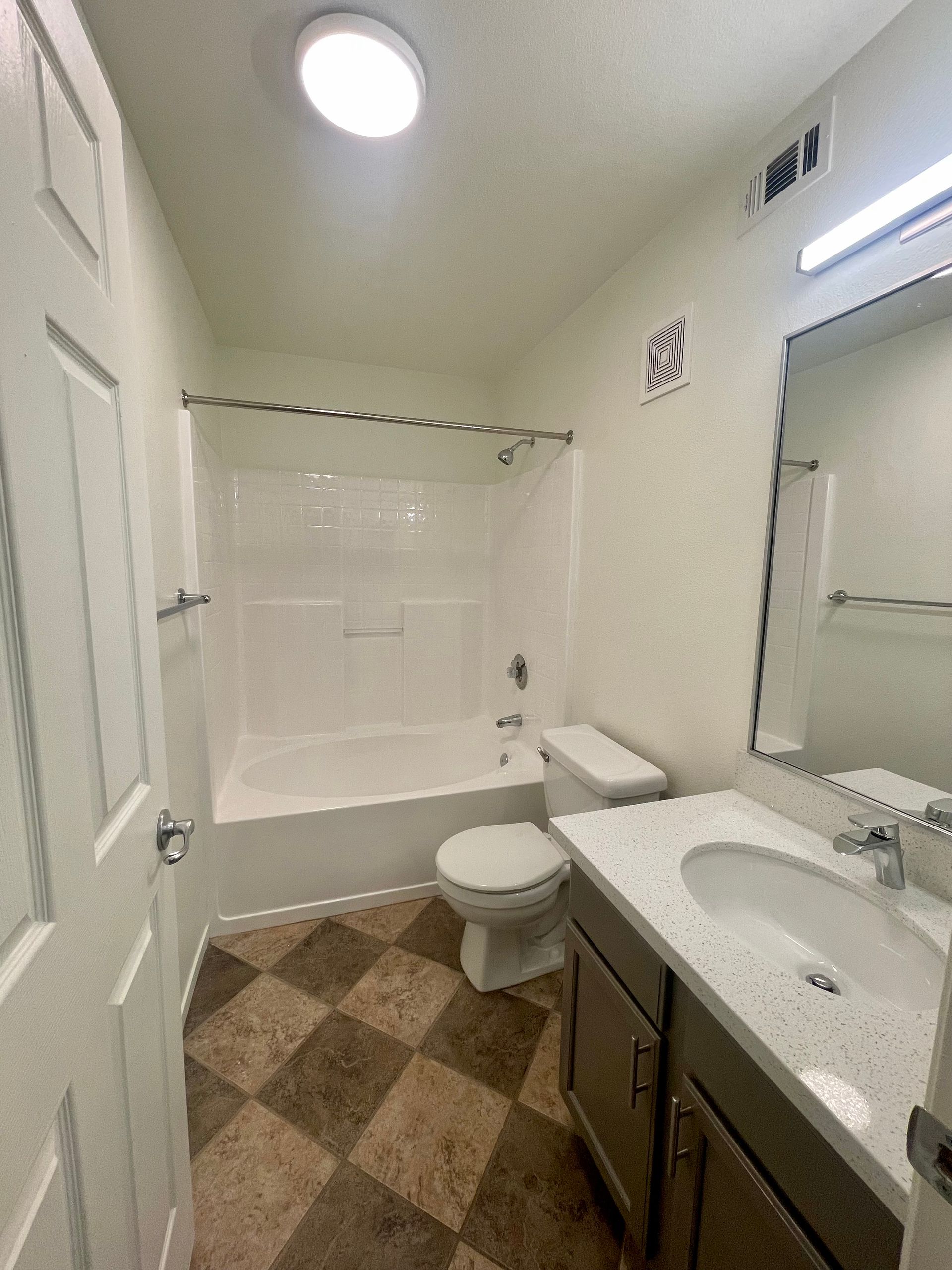 A bathroom with a sink , toilet , bathtub and mirror.