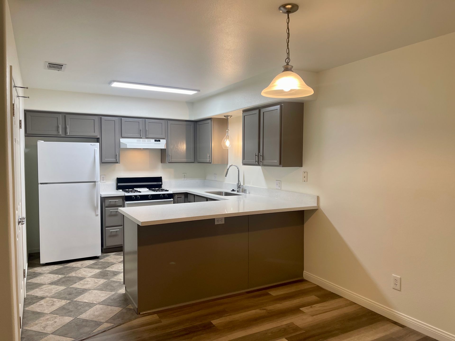 A kitchen with a refrigerator , stove , sink , and cabinets.