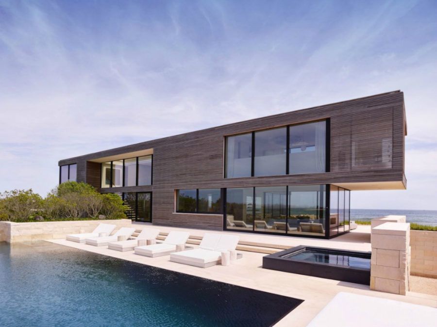 Modern rectangular house with large windows, infinity pool, and ocean view.