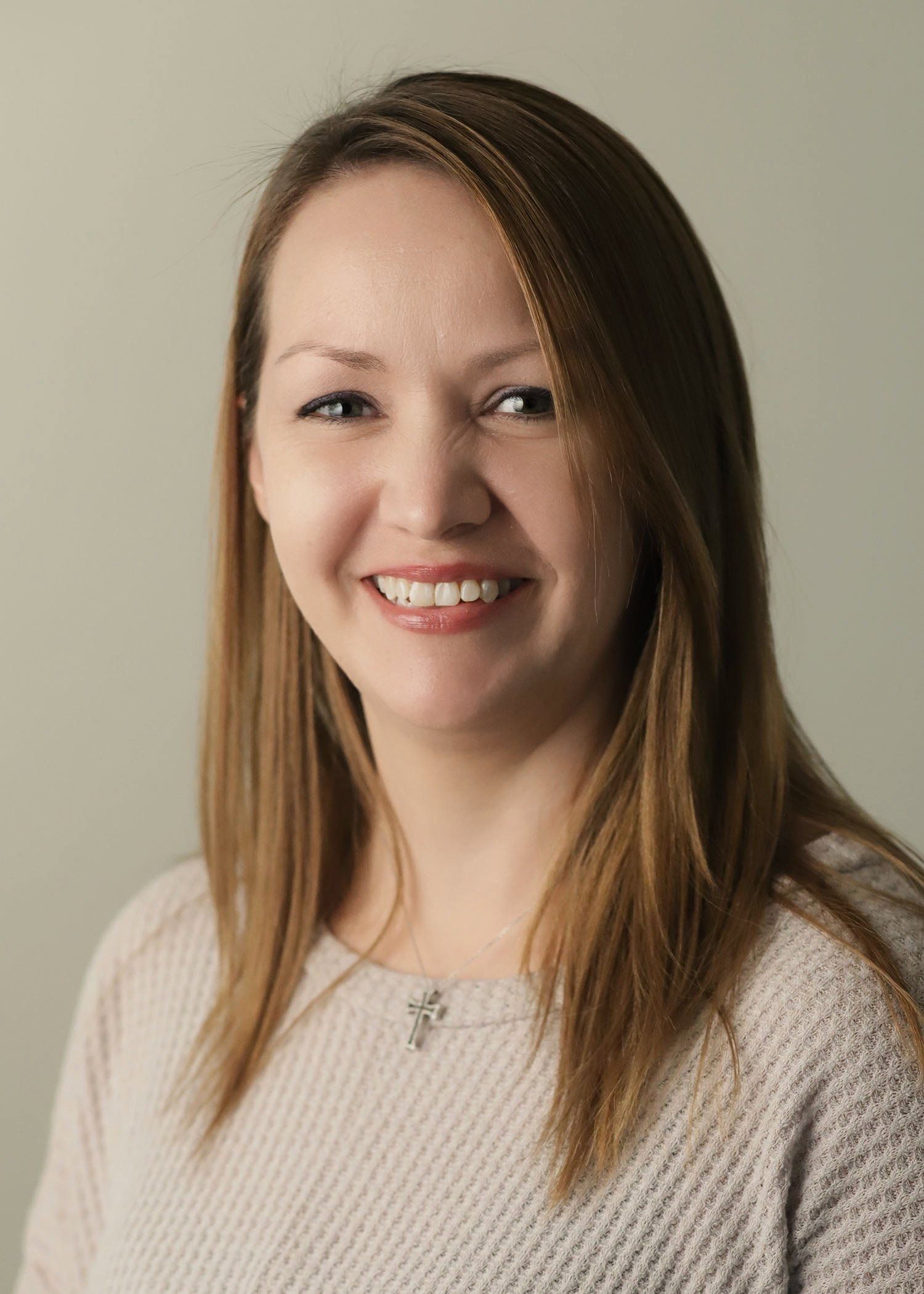 A woman in a pink sweater is smiling for the camera.