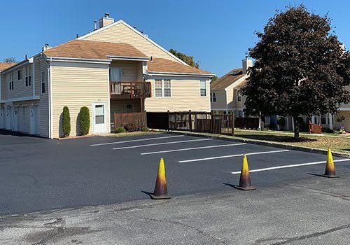 Apartment building with freshly paved parking lot and traffic cones.