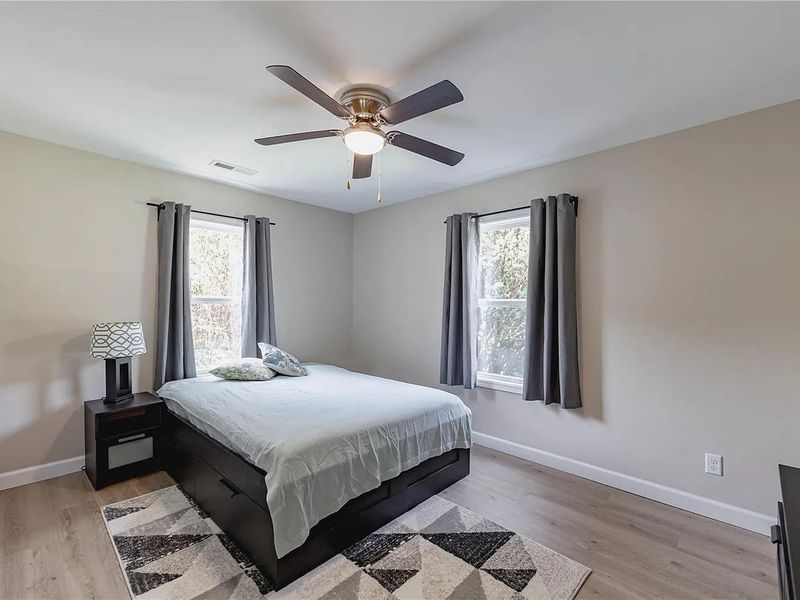 Bedroom with gray walls, dark wood bed, ceiling fan, and black-and-white geometric rug.
