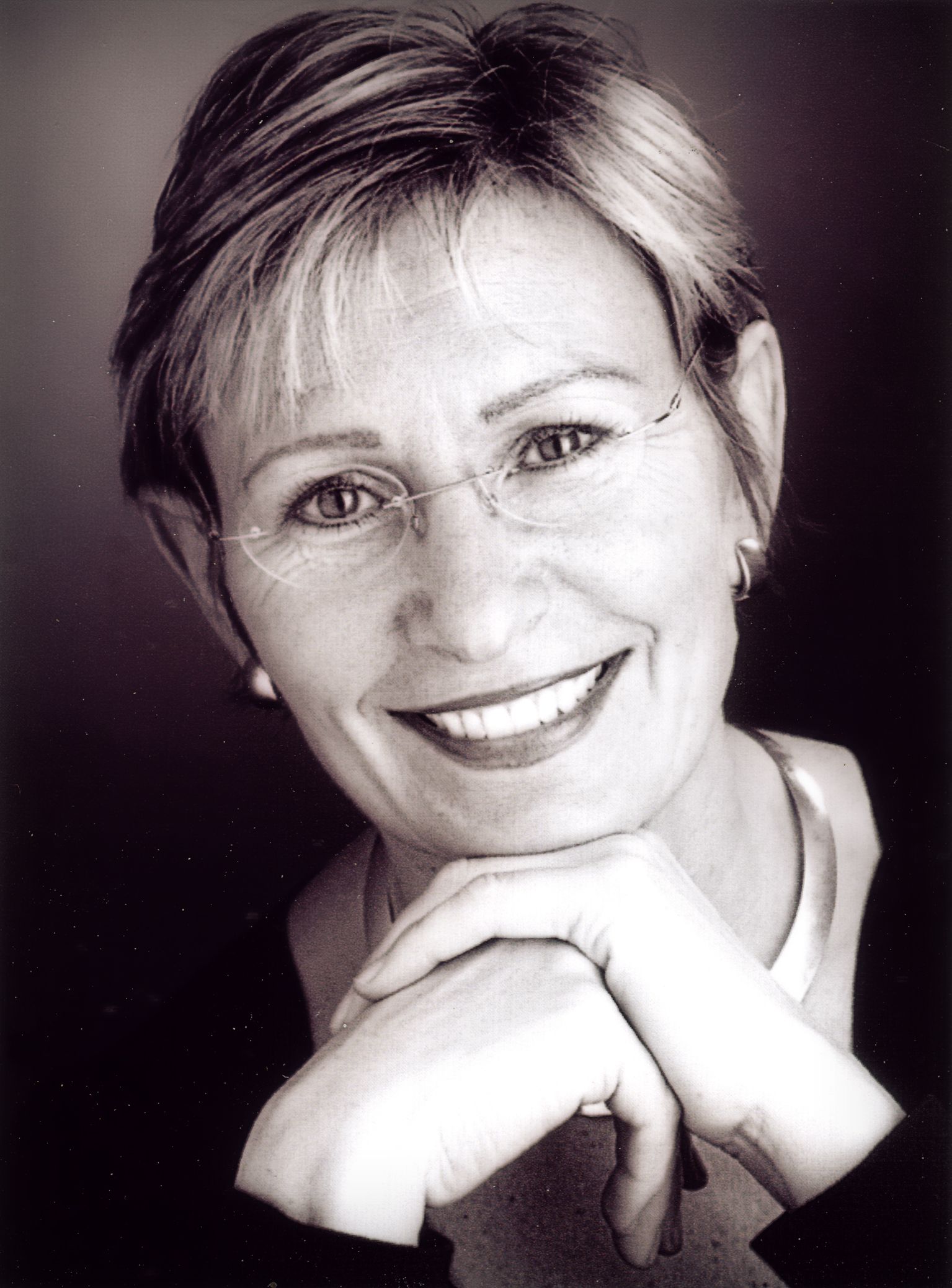 Ein Schwarzweißfoto einer lächelnden Frau mit Brille