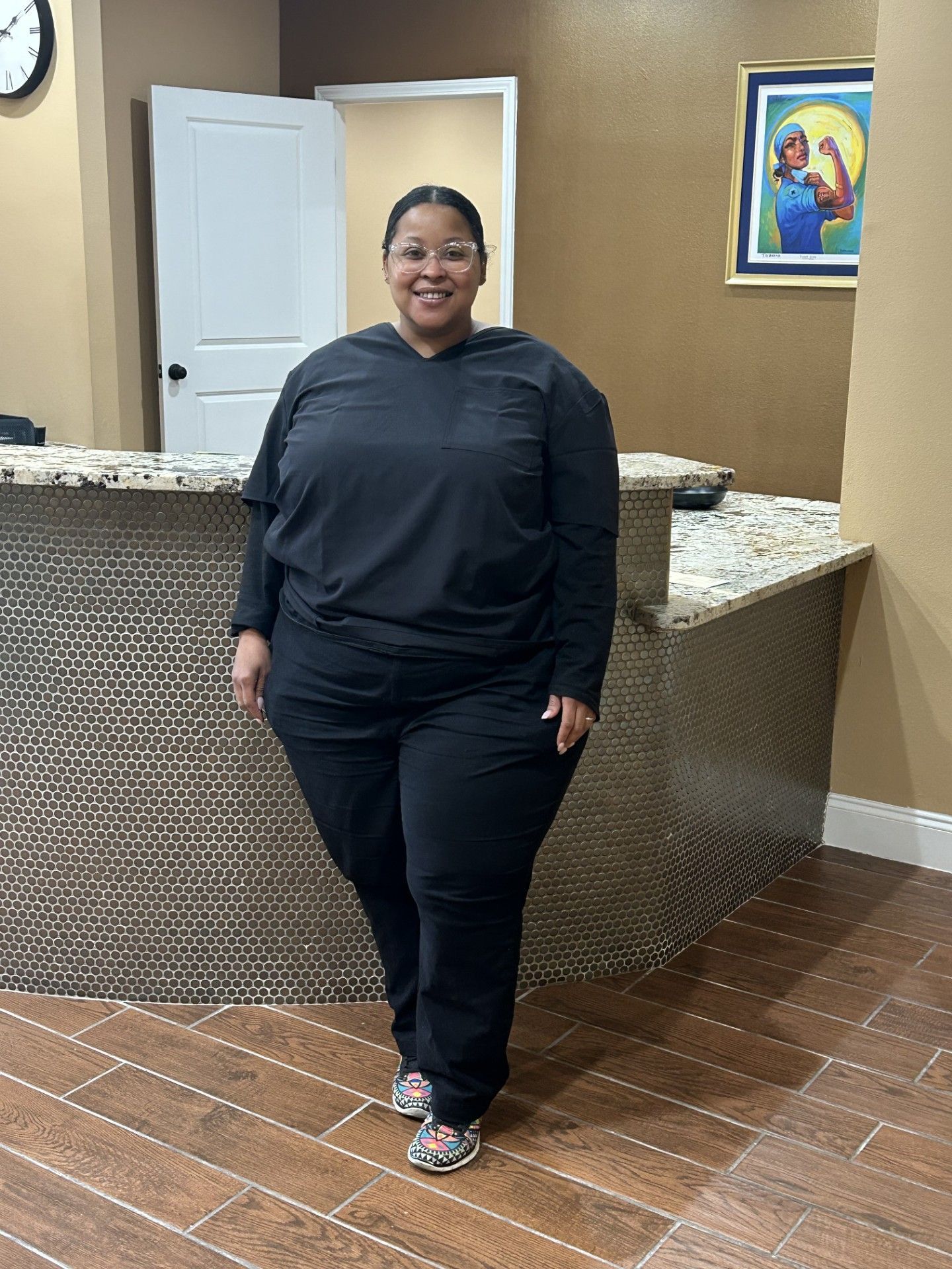 A woman in a black scrub suit is standing in front of a counter. — Picture of Chiropractor in New Orleans, LA