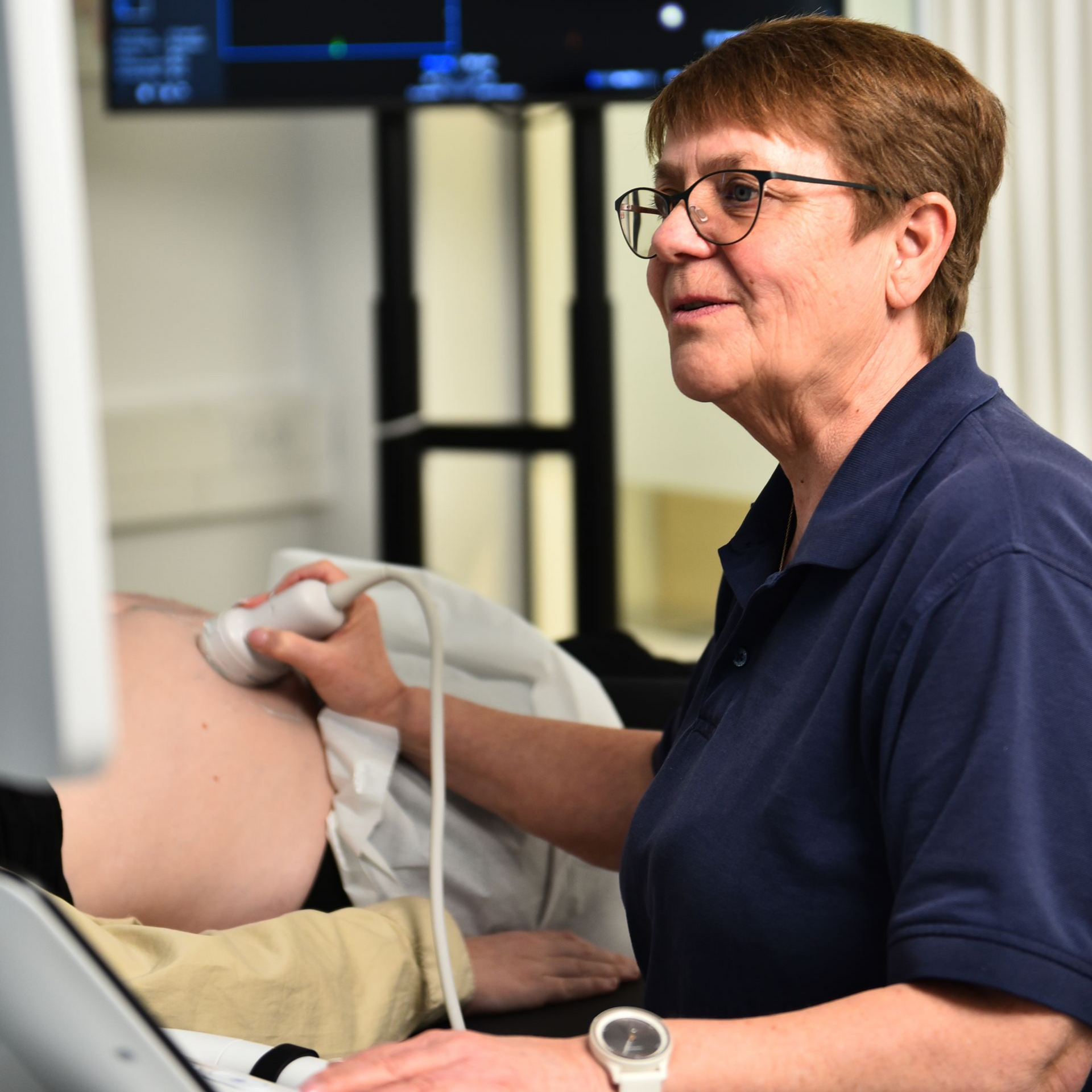 En sundhedsperson udfører en ultralydsundersøgelse på en patient i et klinisk miljø.