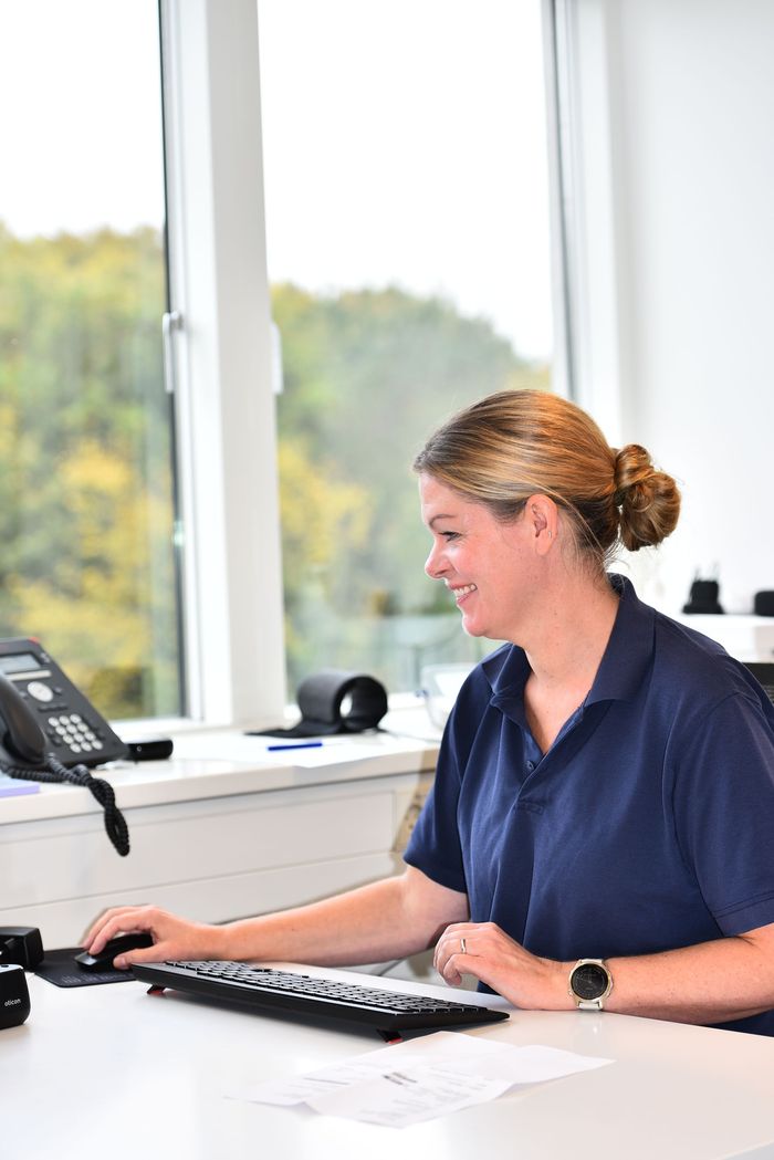 Kvinde justerer VR-headsettet på en anden person; smilende, indendørs, hos Charlottenlund privathospital.