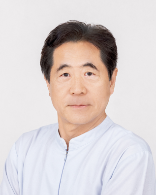 Smiling Asian woman in a white lab coat, possibly a doctor, against a blurred background.