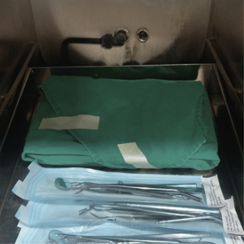 Dental tools in sterilized packages and on a tray, with a paper illustrating the instruments.