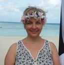 A woman wearing a flower crown is standing on a beach.