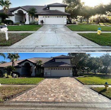 Townhouse with a driveway bordered by brick pavers and green grass.