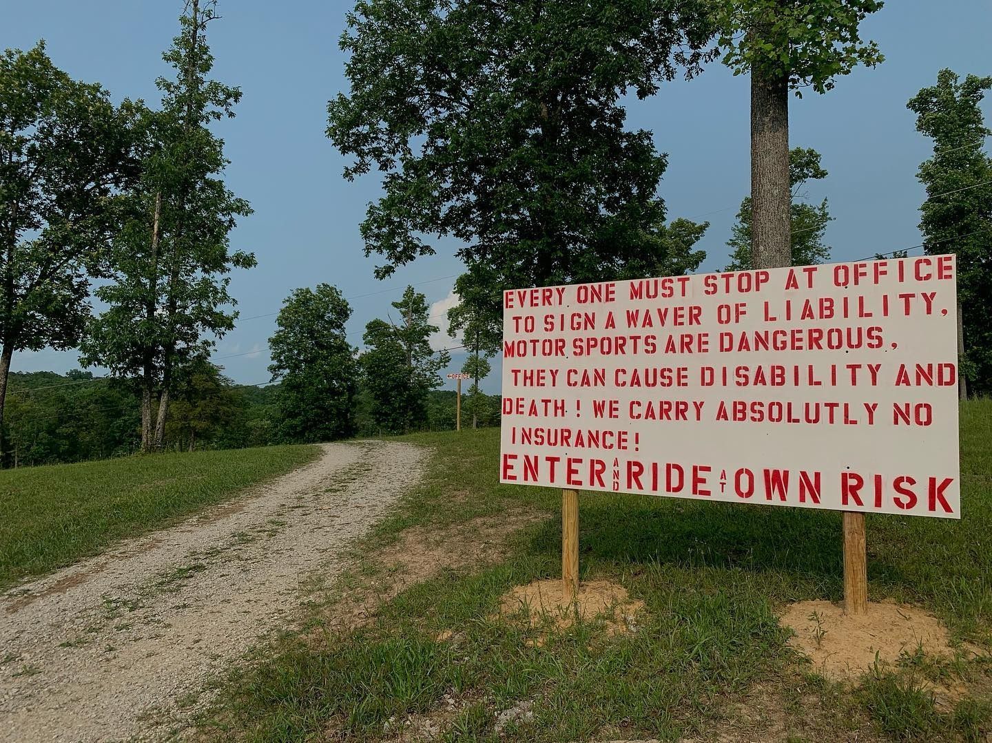 A sign in a grassy field reads, 