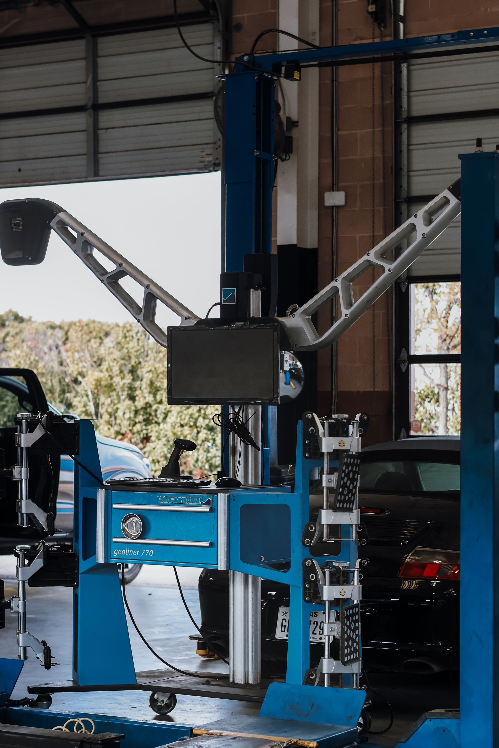 Blue and silver car alignment machine in a garage setting with a car visible. | Euro Auto Repair