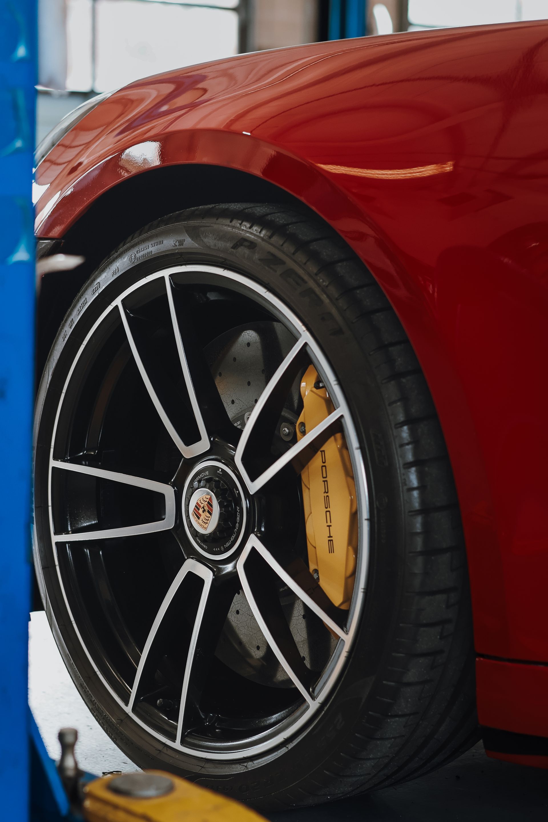 Red car wheel with black and silver rim, yellow brake caliper, tire. | Euro Auto Repair