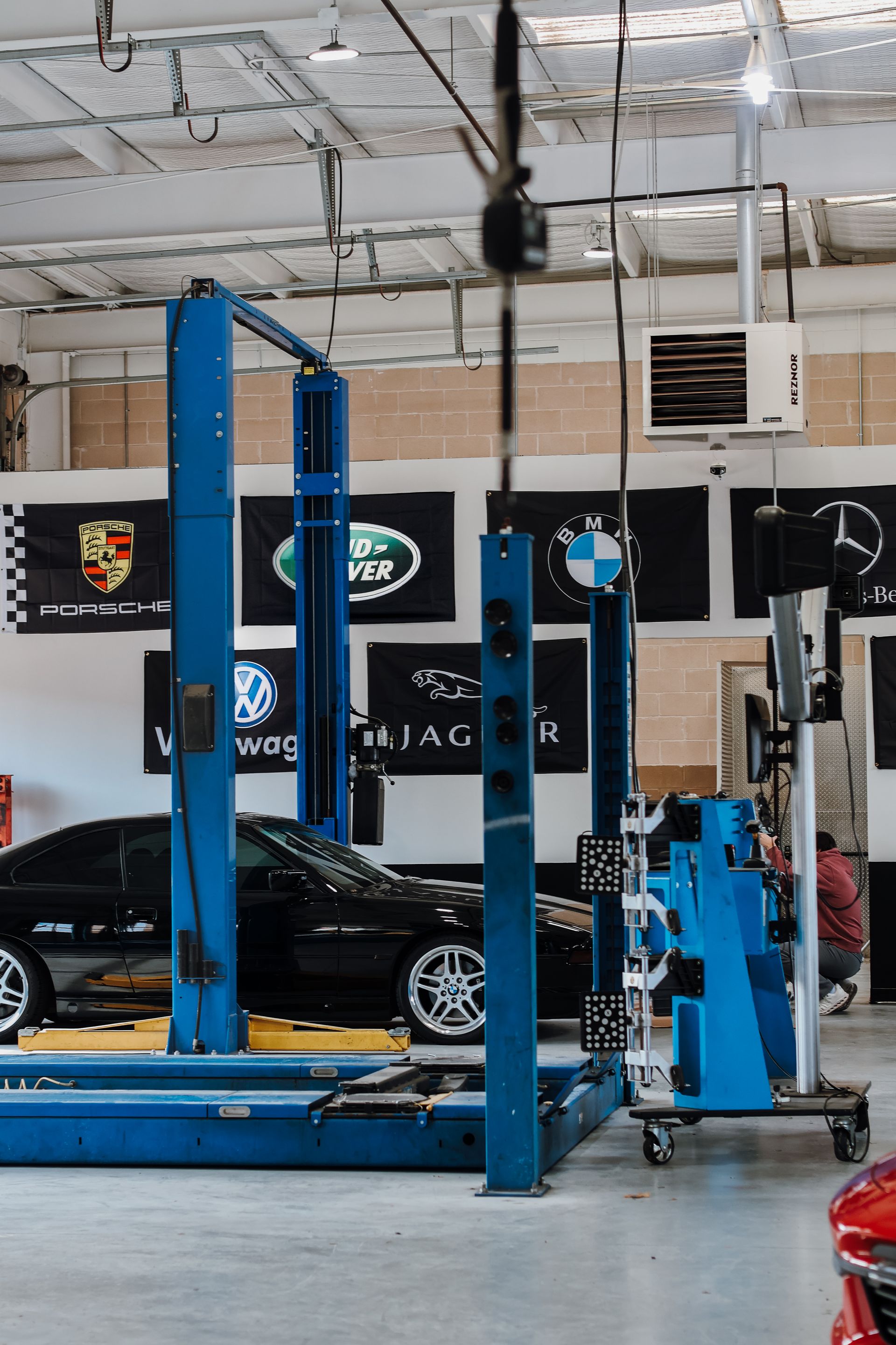 Car lift in auto repair shop with black cars and brand flags. | Euro Auto Repair