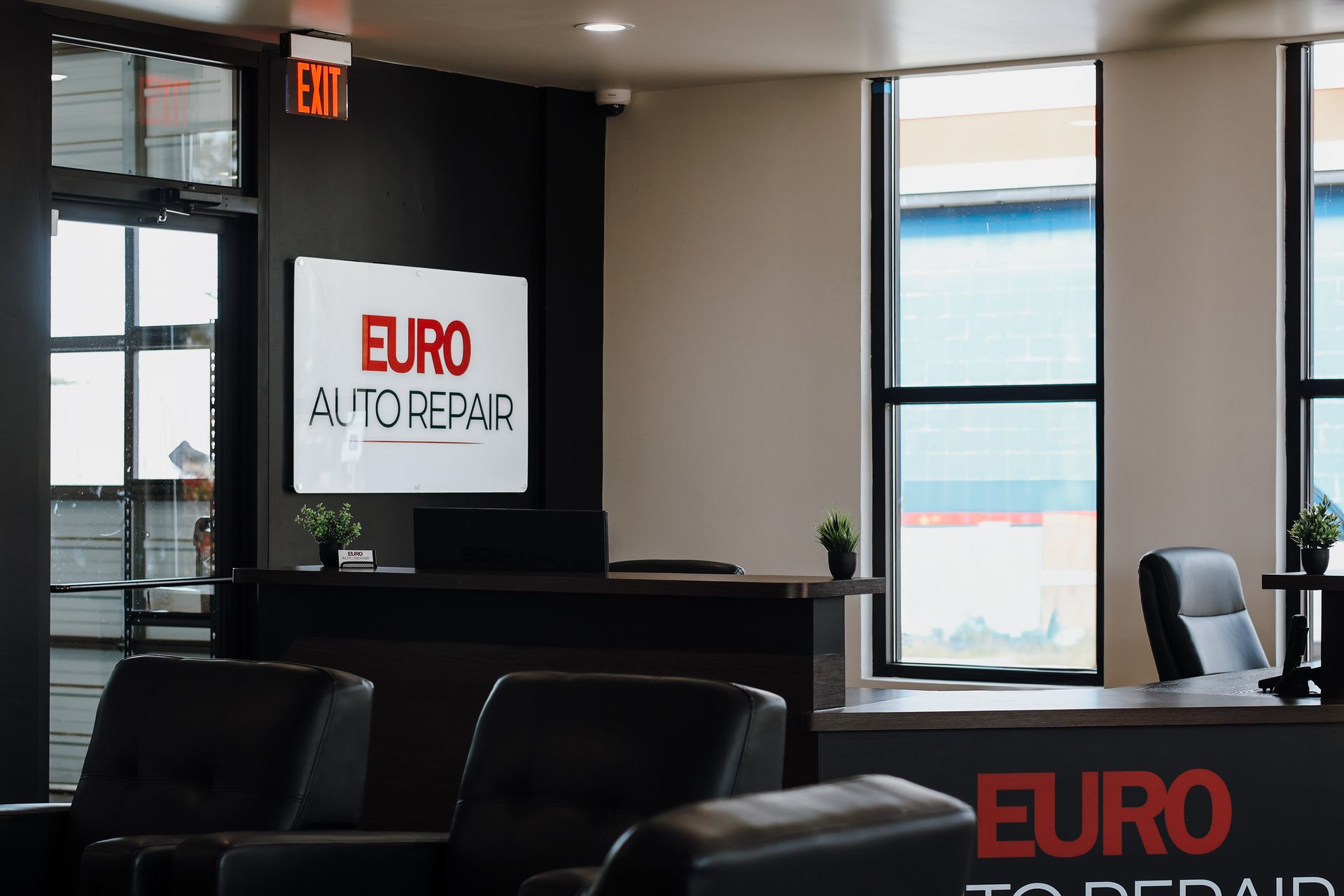 Interior of Euro Auto Repair office with reception desk, chairs, and large sign. | Euro Auto Repair