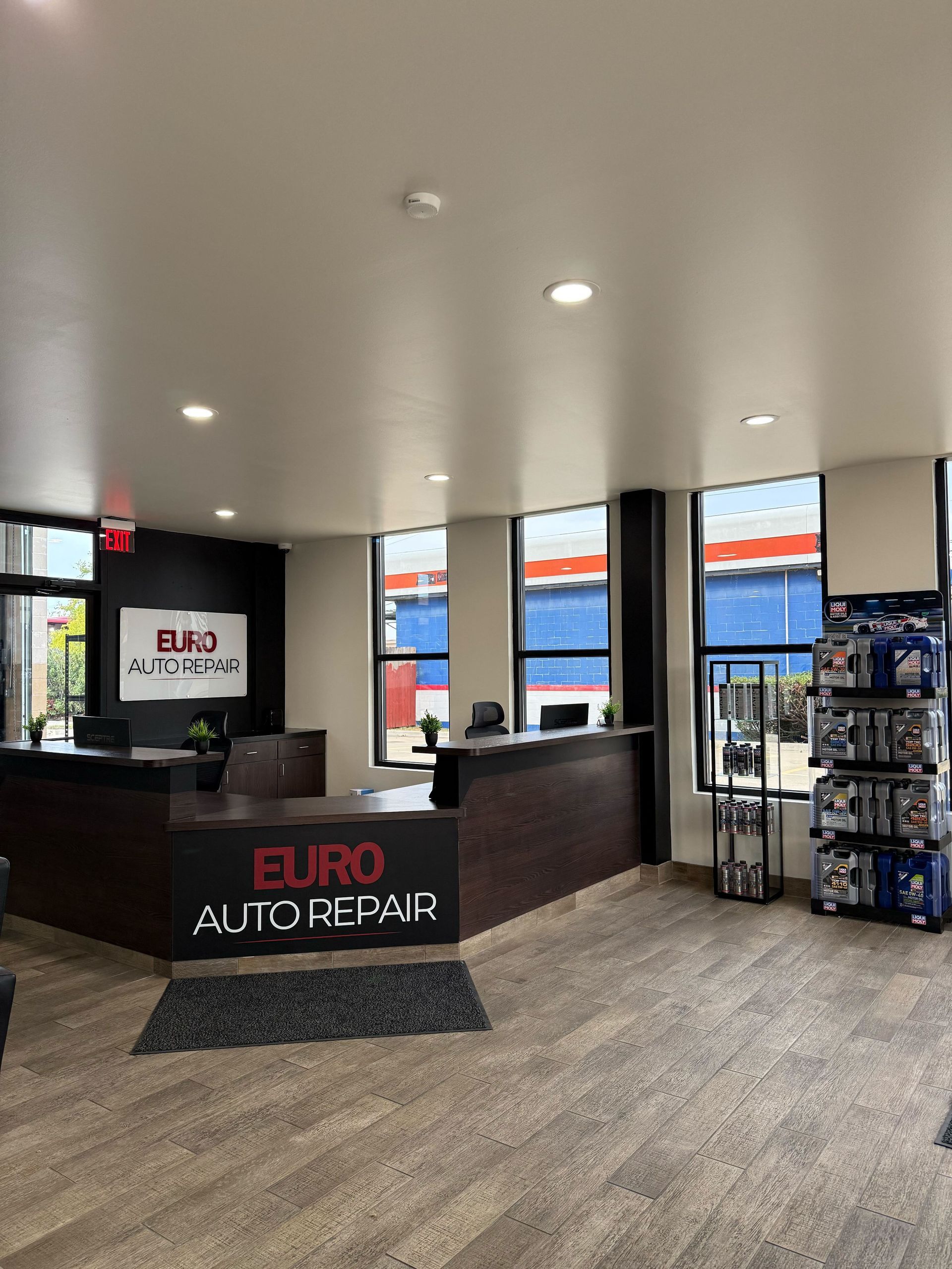 Interior of Euro Auto Repair office, with dark brown reception desks, logo, and large windows | Euro Auto Repair