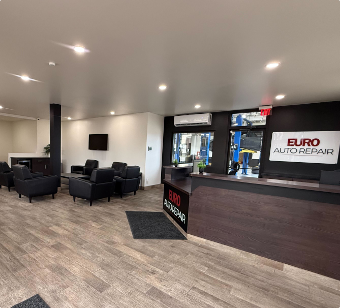Interior of Euro Auto Repair waiting area with seating, reception desk, and car lift visible through windows | Euro Auto Repair