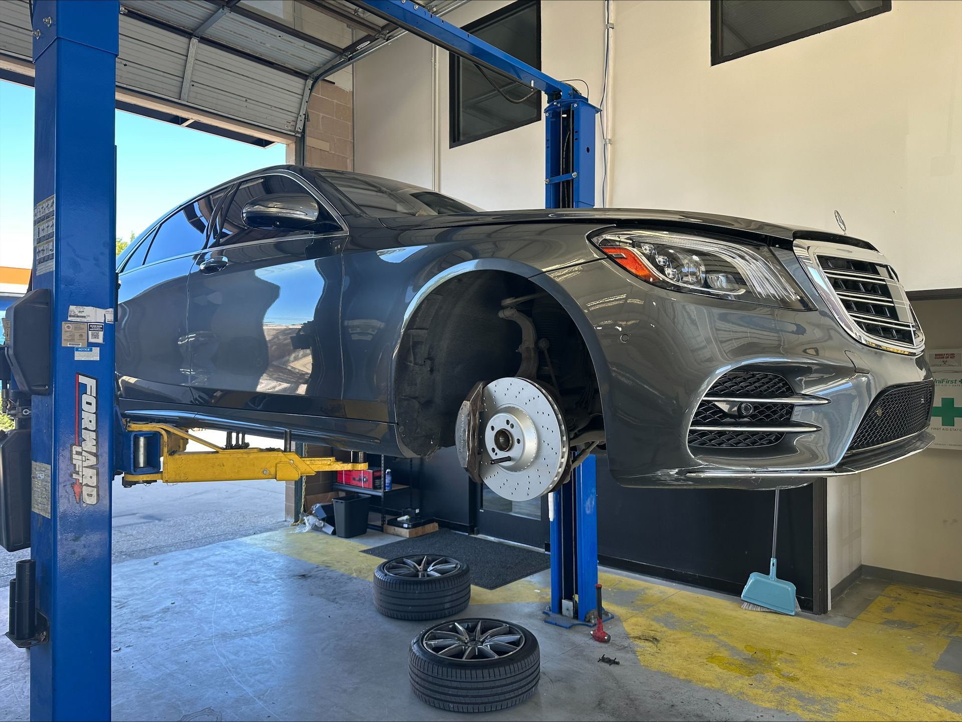 Gray Mercedes sedan on a car lift in a repair shop; tires removed | Euro Auto Repair