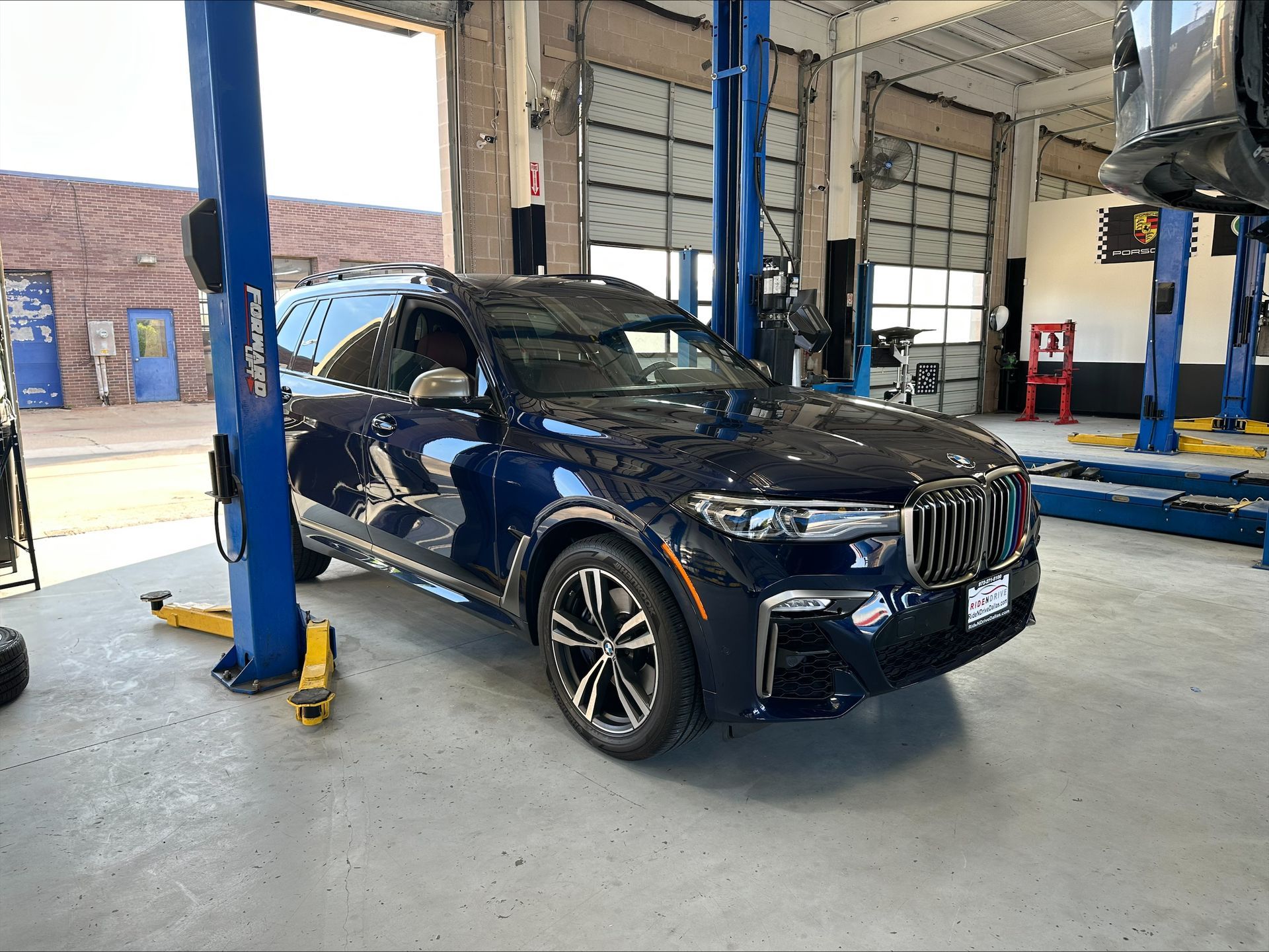 Blue SUV in a garage bay, elevated on a lift. Sunlight streams in | Euro Auto Repair