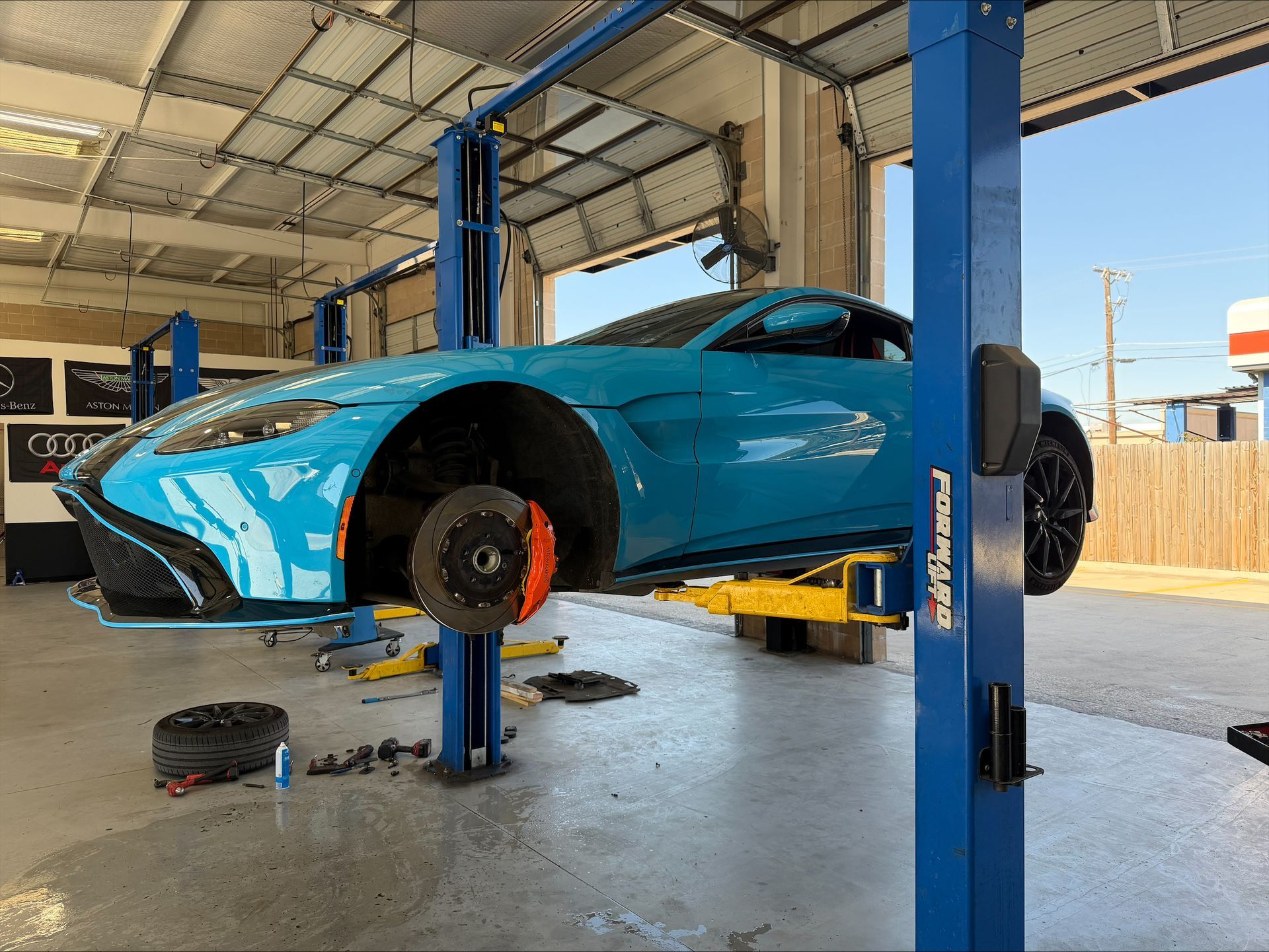 Blue sports car on a lift in a garage, brake rotor exposed | Euro Auto Repair