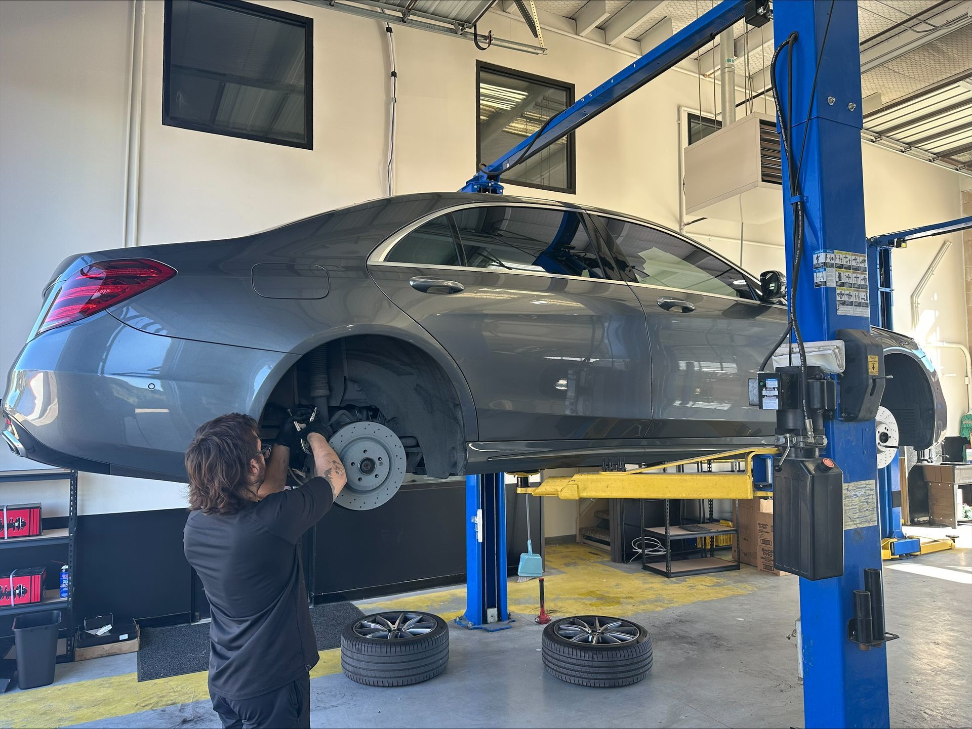 Mechanic working on a grey car lifted on a hoist in a garage | Euro Auto Repair