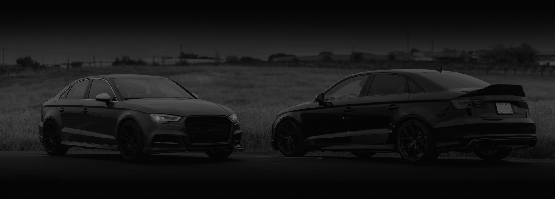 Two black cars parked on a road. One car is facing forward, the other is facing backward. | Euro Auto Repair