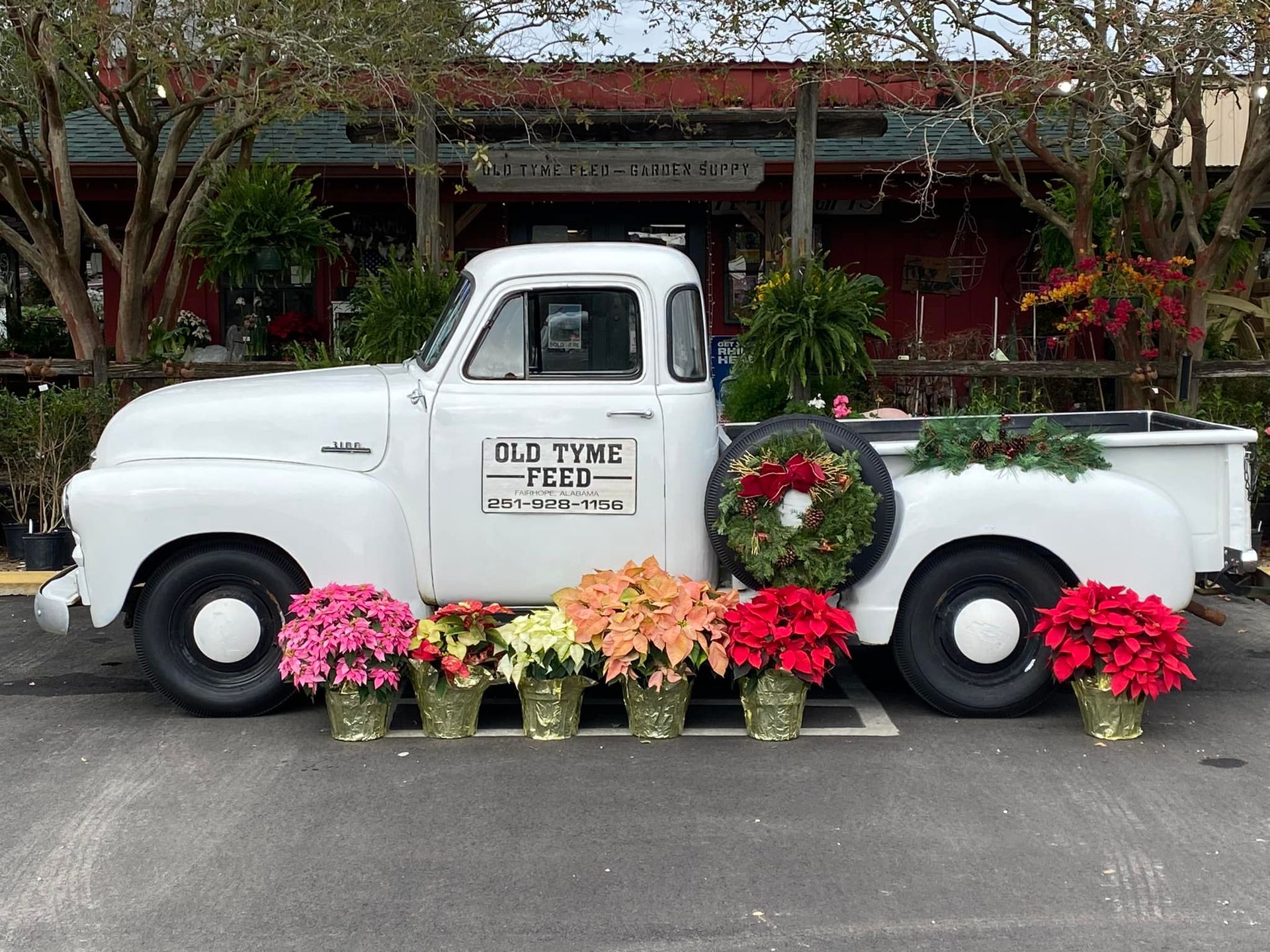 A white truck is decorated with flowers and a wreath.