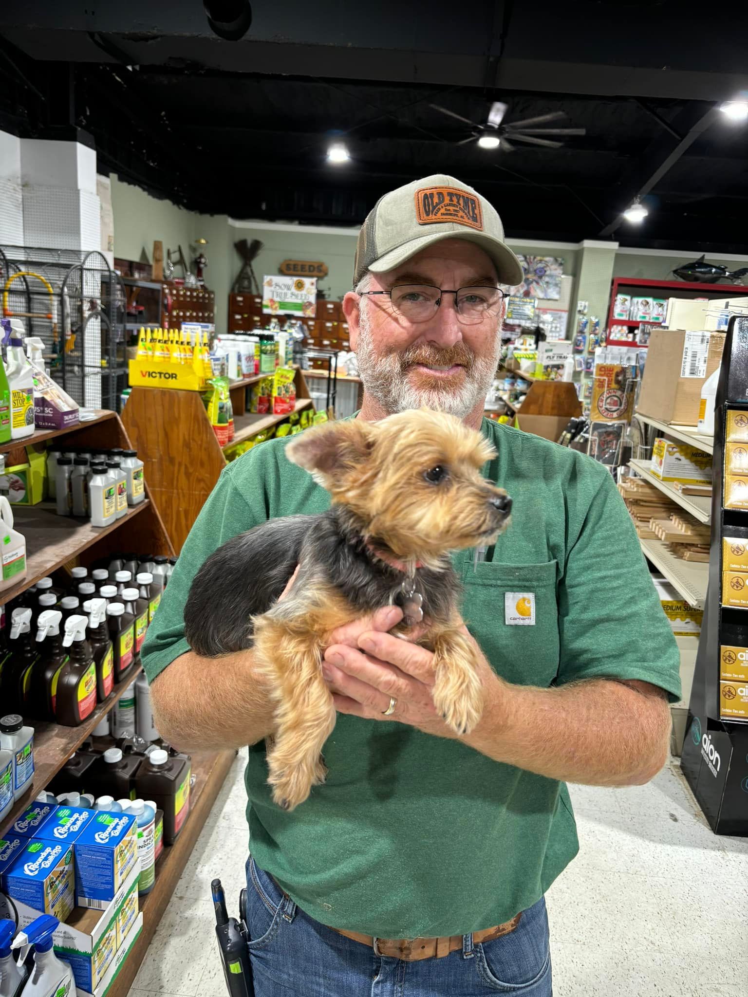 A man is holding a small dog in his arms in a store.