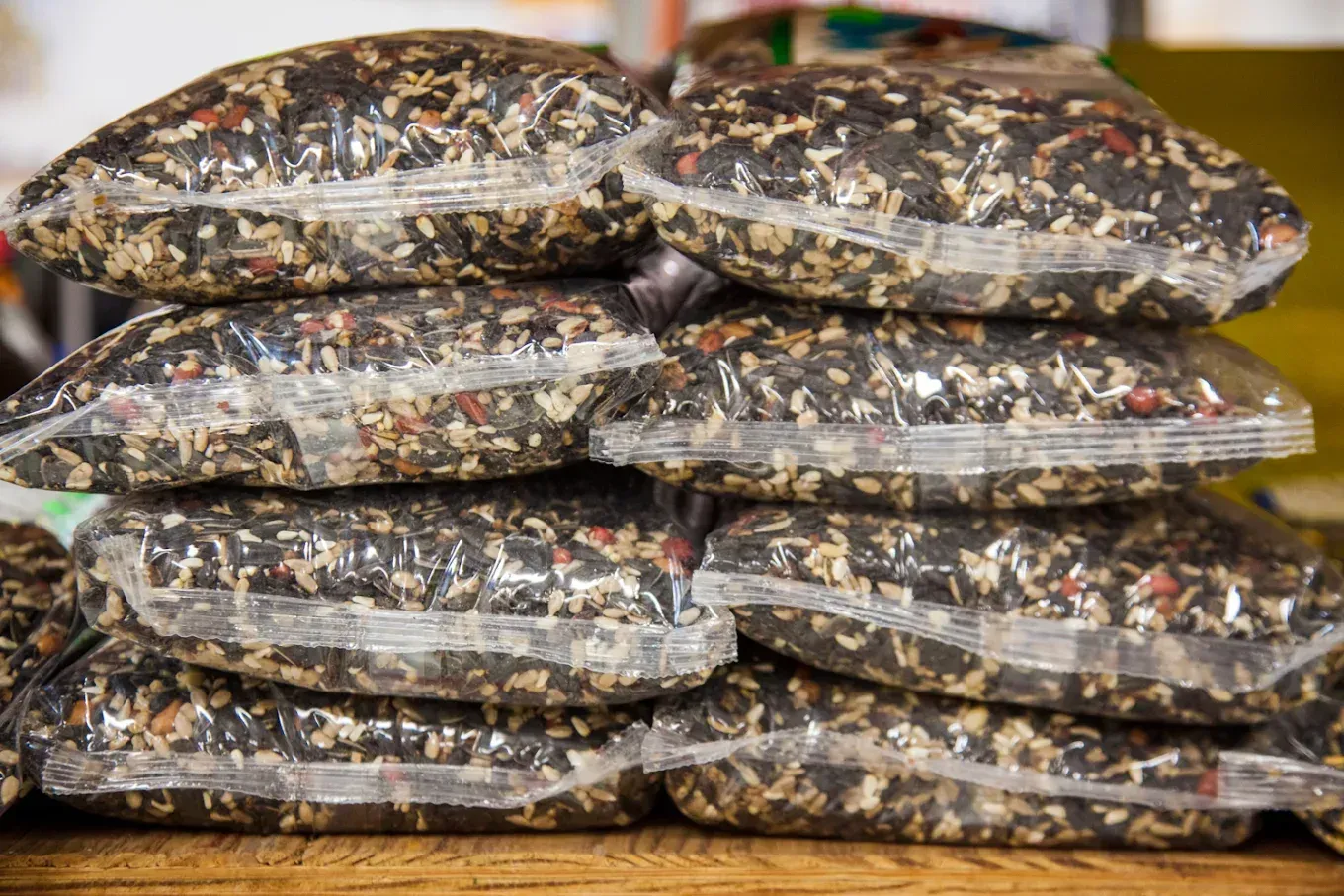 A pile of bags of food are stacked on top of each other on a wooden table.