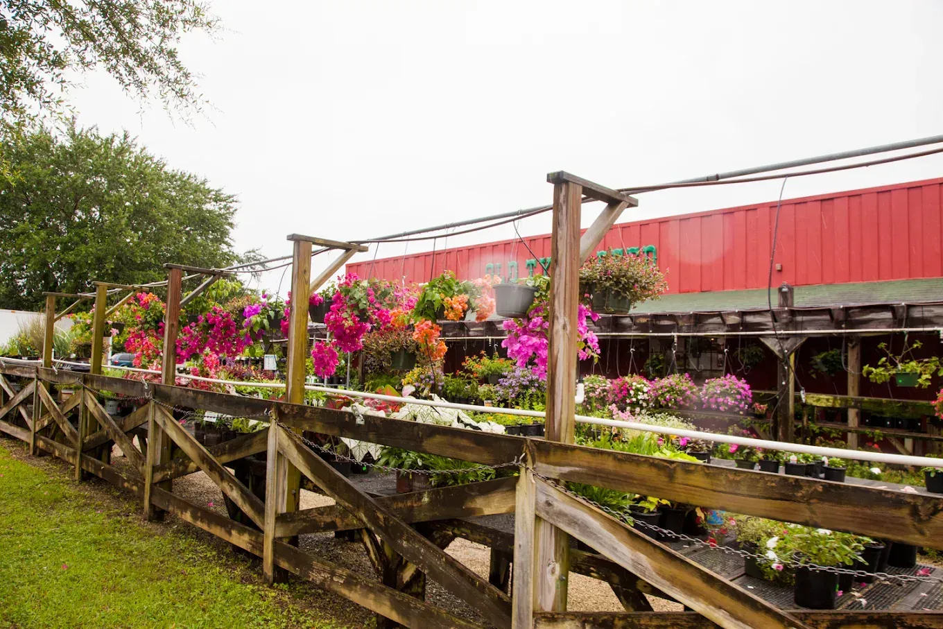 A wooden fence surrounds a garden center filled with lots of potted plants.