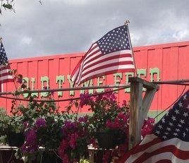 An american flag is flying in front of a red building