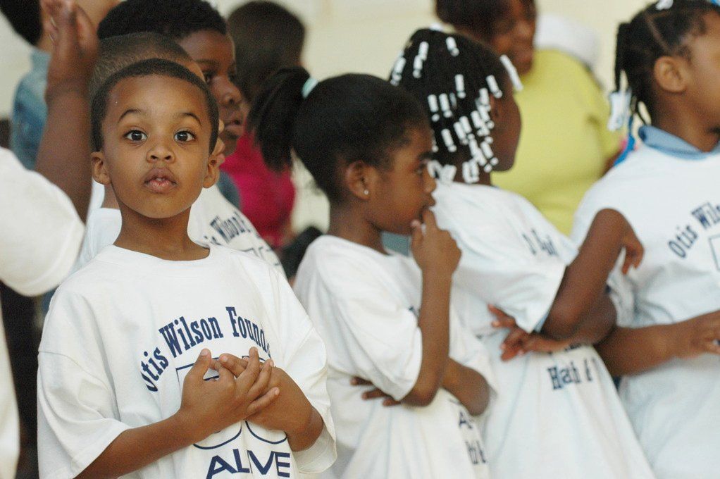 A group of children wearing white shirts that say alive