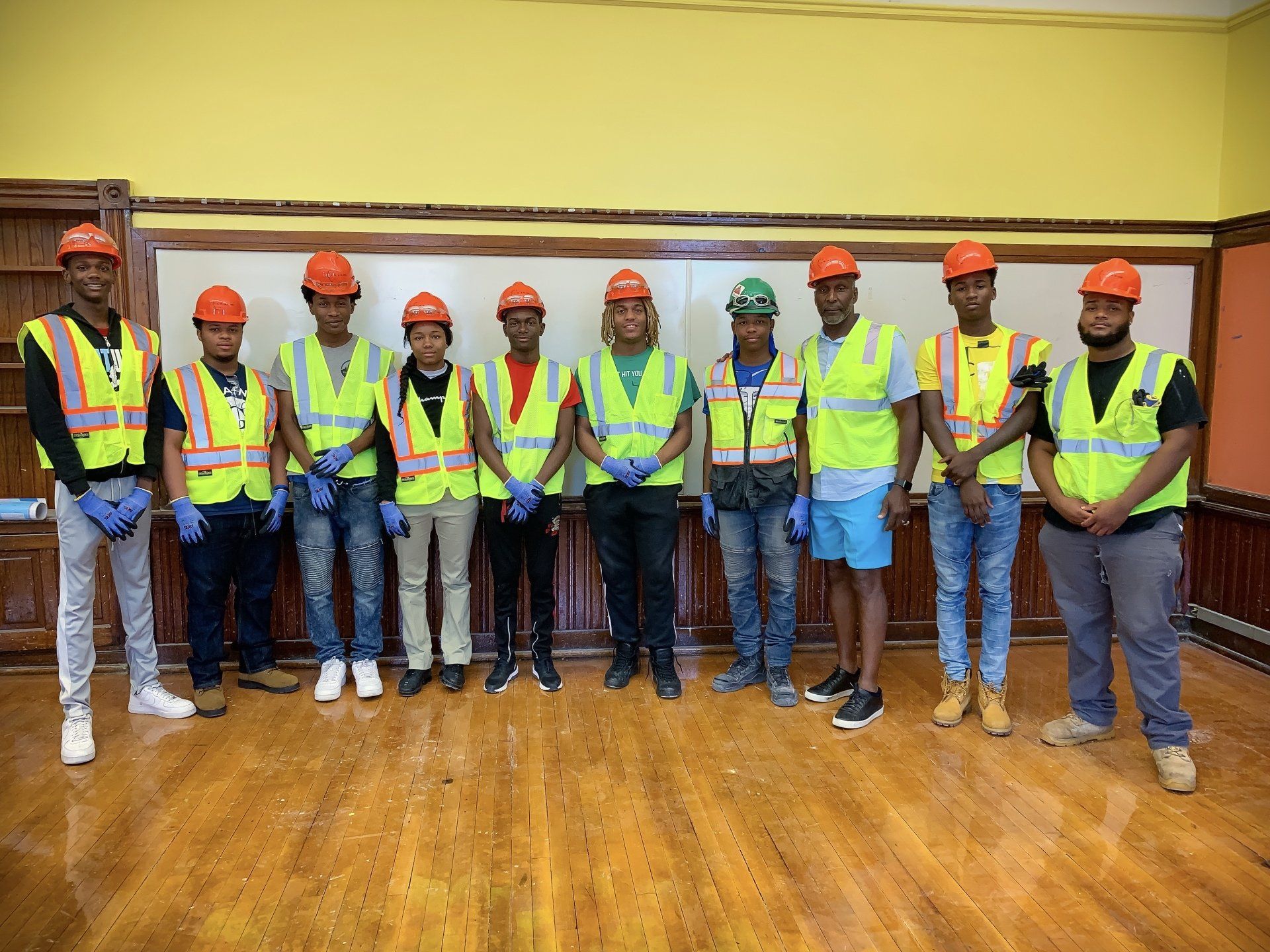 A group of construction workers are posing for a picture in a room.