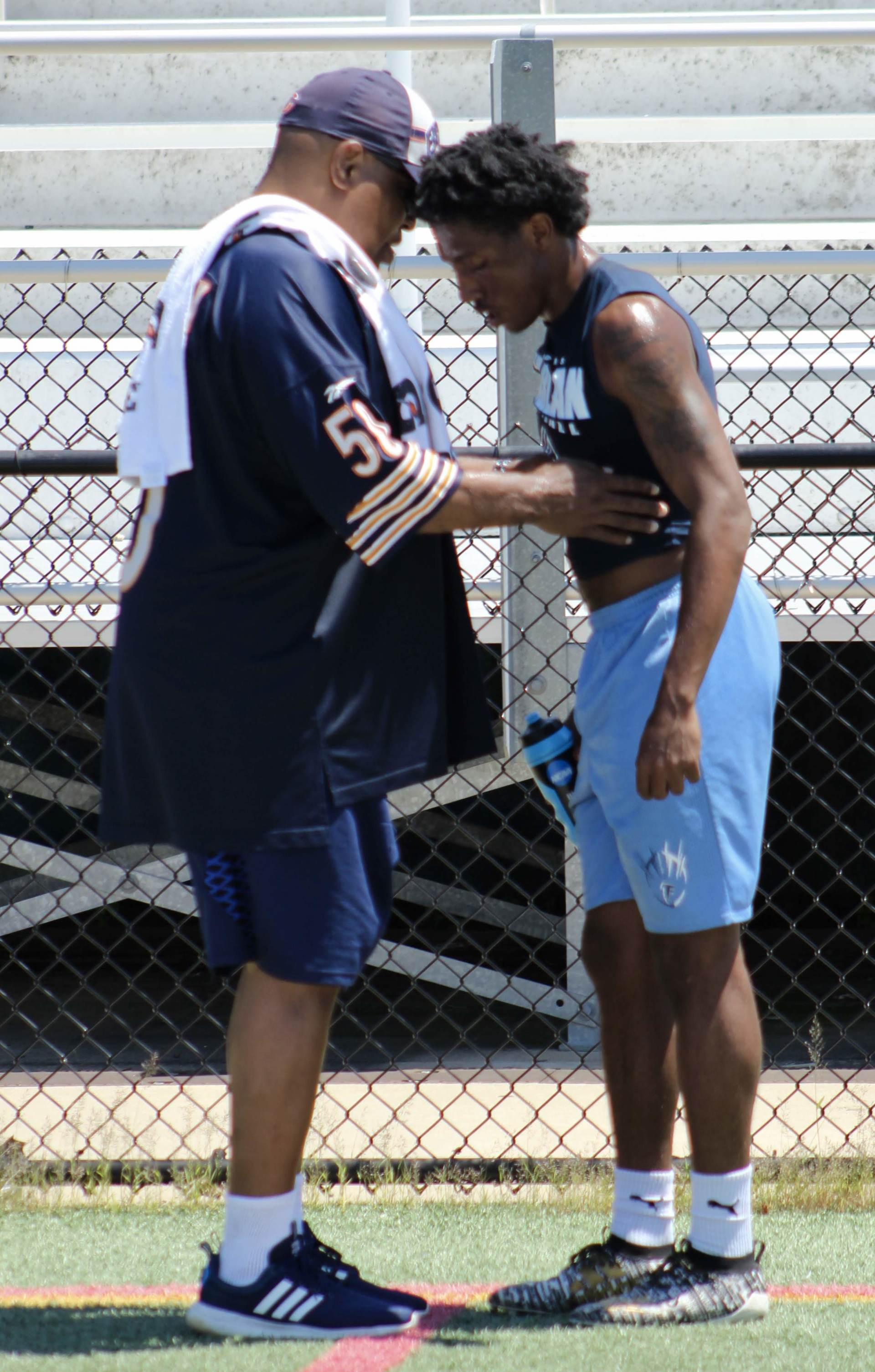 A man is talking to a young man on a field.