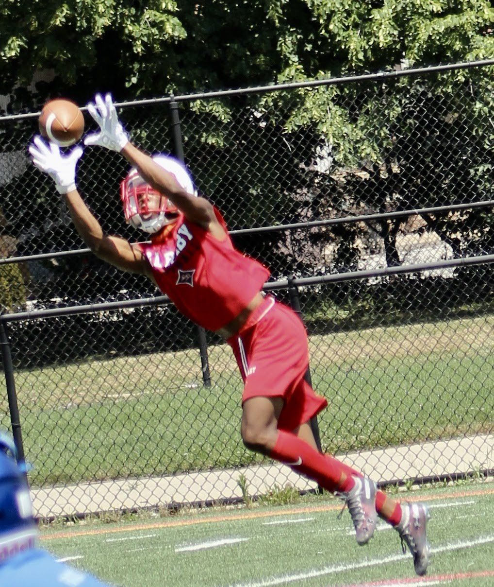 A football player in a red uniform is trying to catch a ball
