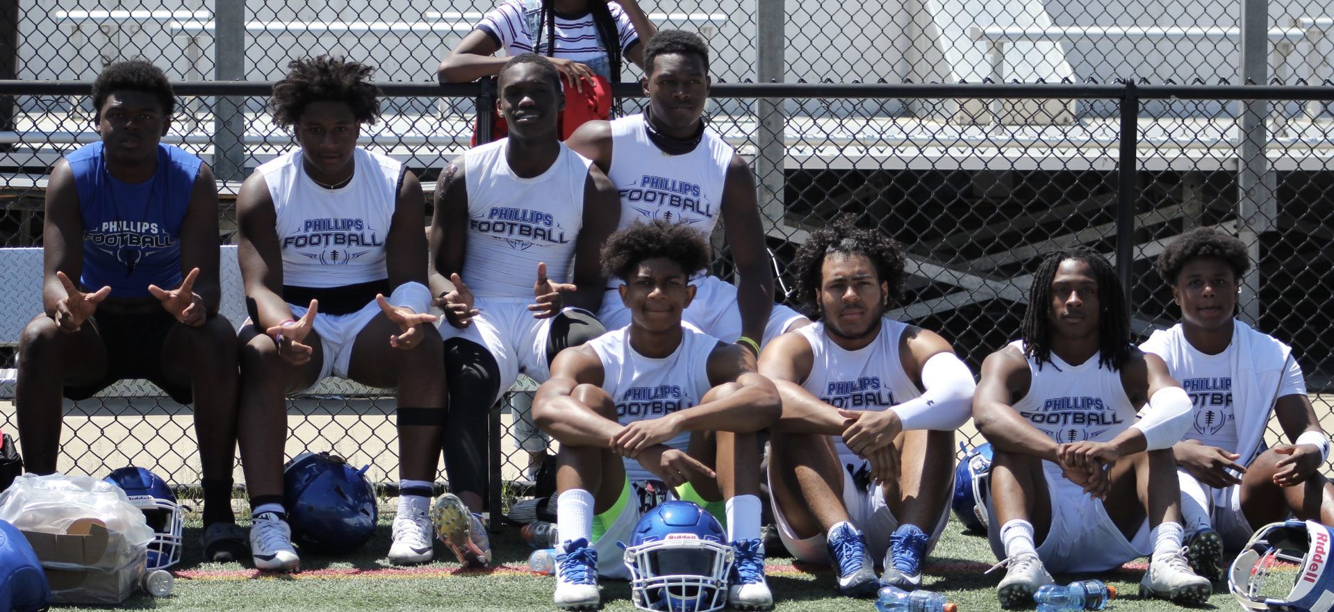 A group of young men are sitting on a bench on a football field.