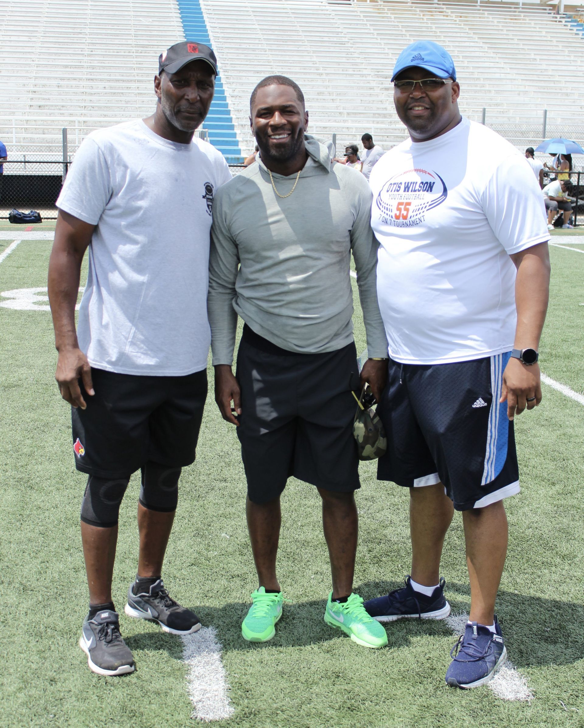 Three men are posing for a picture on a football field
