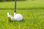 Golf ball on green grass with golf club.
