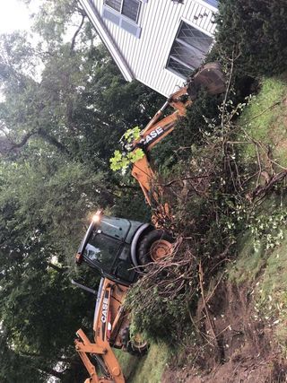 A bulldozer is digging a hole in front of a house.