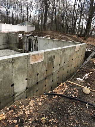 A large concrete wall is being built in the middle of a forest.