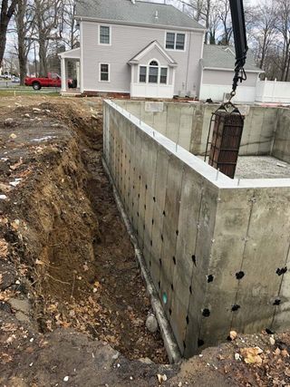 A large concrete wall is being built in front of a house.