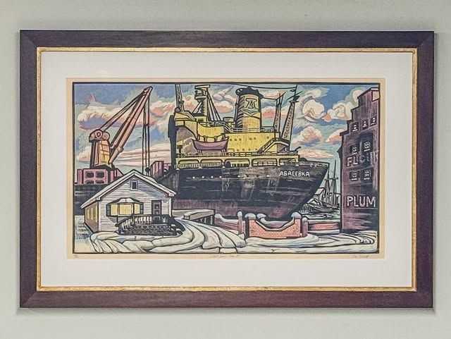 Framed woodblock print of a large industrial ship docked beside a small house and a factory building with a crane.