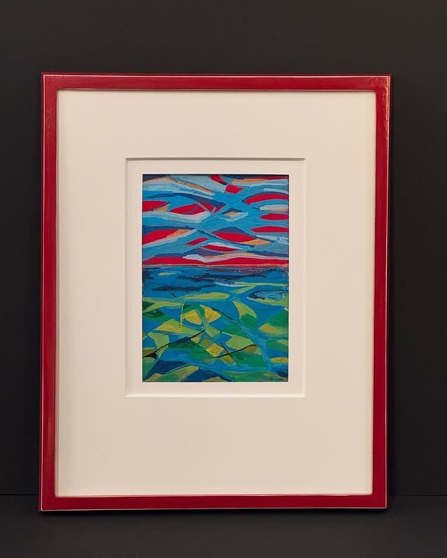 Framed artwork featuring a landscape with a blue and red sky over a textured blue and green sea.